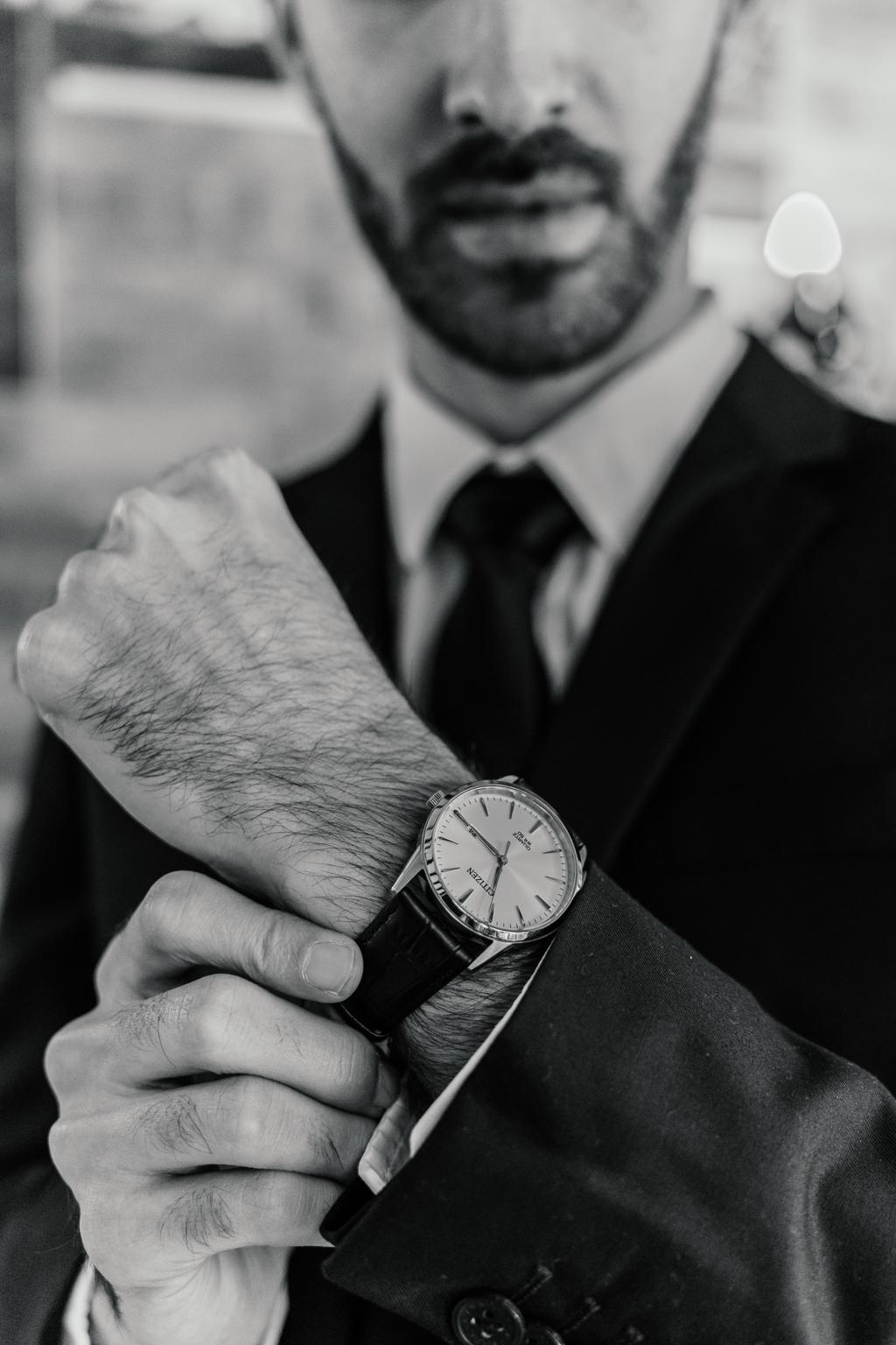 Black-and-white close-up of the groom adjusting his watch and suit cuff, Gunther and Lara's wedding
