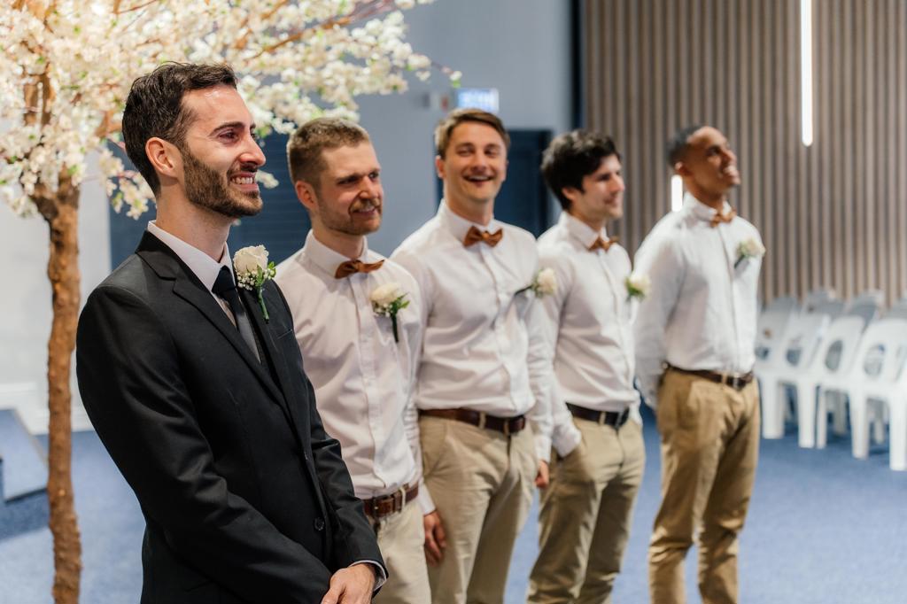 The groom and groomsmen smiling as they wait at the ceremony