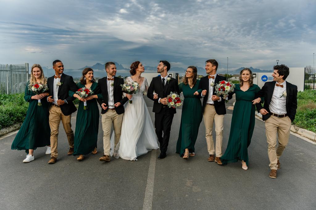 The bridal party walking down a road, the bridesmaids in emerald green dresses, Gunther and Lara's wedding