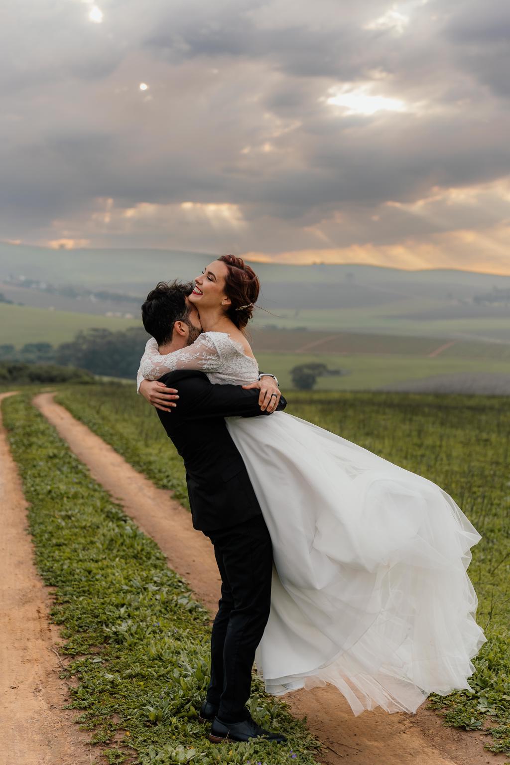 The groom lifting the bride on a farm track under a cloudy evening sky, Gunther and Lara's wedding