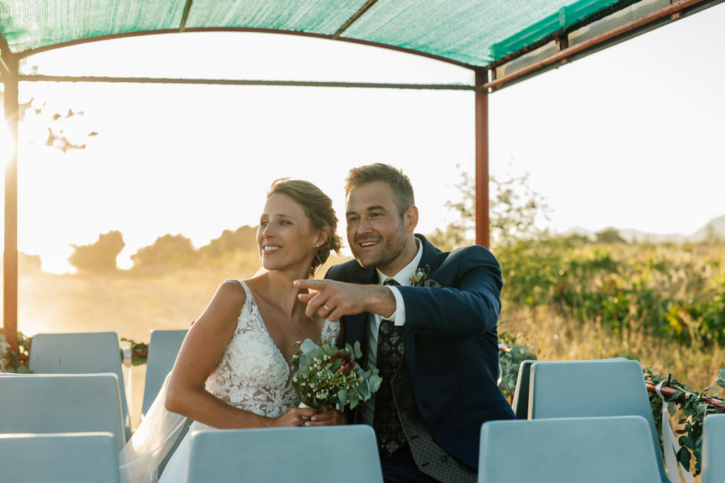Bride and groom laughing together under a shade canopy