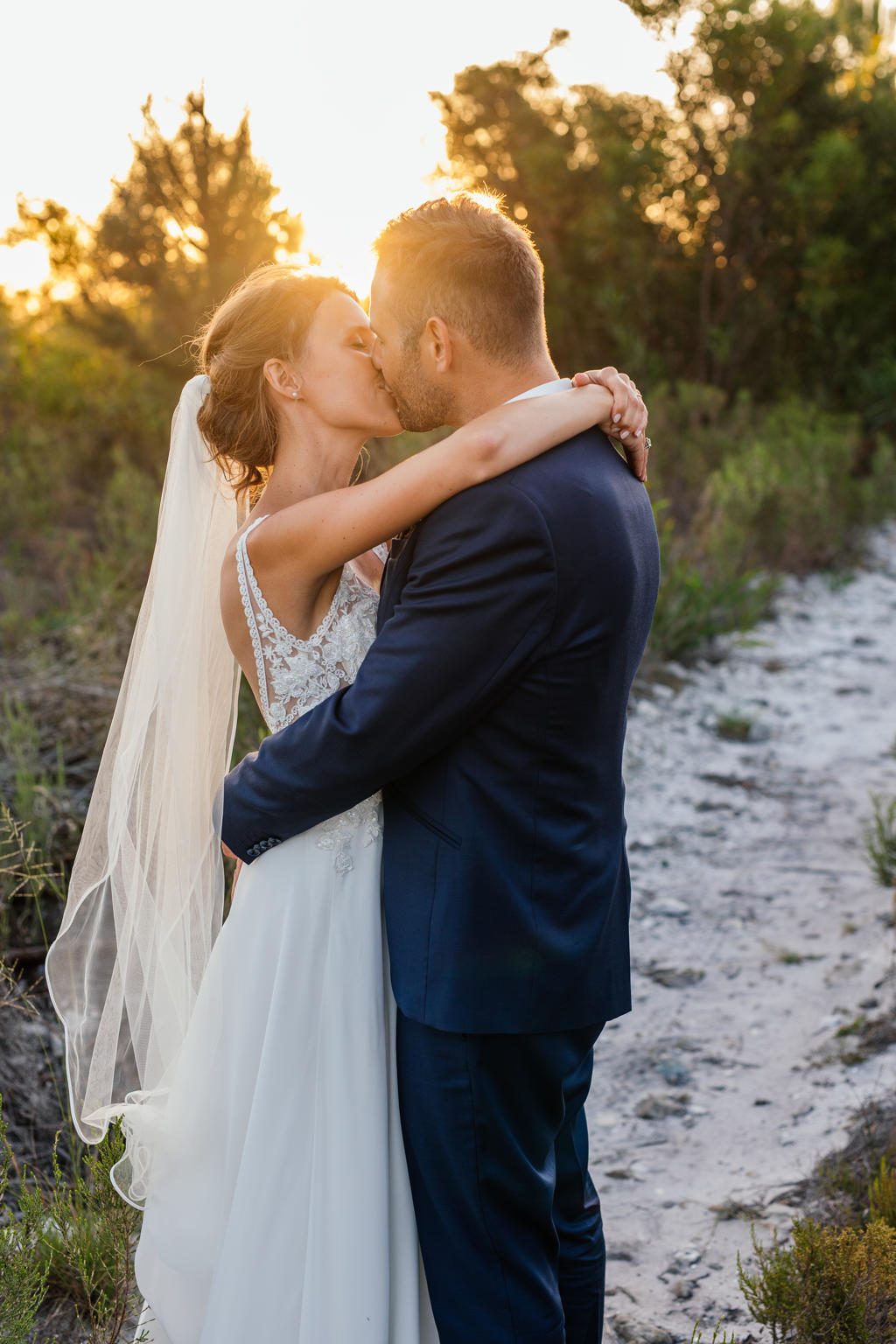 Bride and groom kissing on a sandy path in the late afternoon sun, Ian and Katharina's wedding