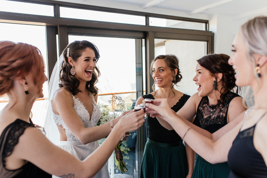 The bride and her bridesmaids raising a toast while getting ready