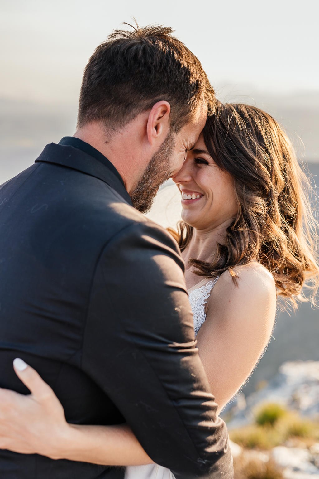 Bride and groom forehead to forehead, smiling, on a mountain top, IW and Tarien's wedding