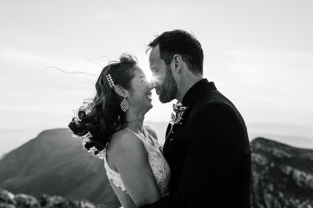 Black-and-white photo of the bride and groom nose to nose on a windy mountain top, IW and Tarien's wedding