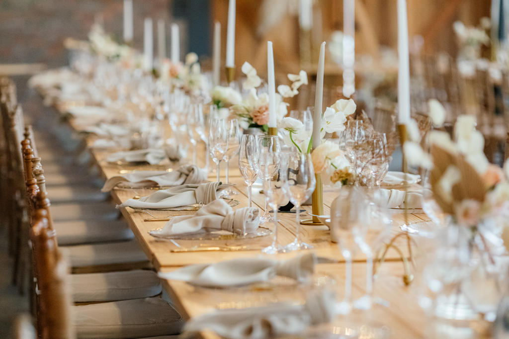 A long reception table set with candles, glassware and pale flowers, Ulrich and Keshia's wedding