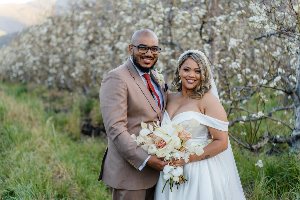Bride and groom standing together in a blossoming orchard