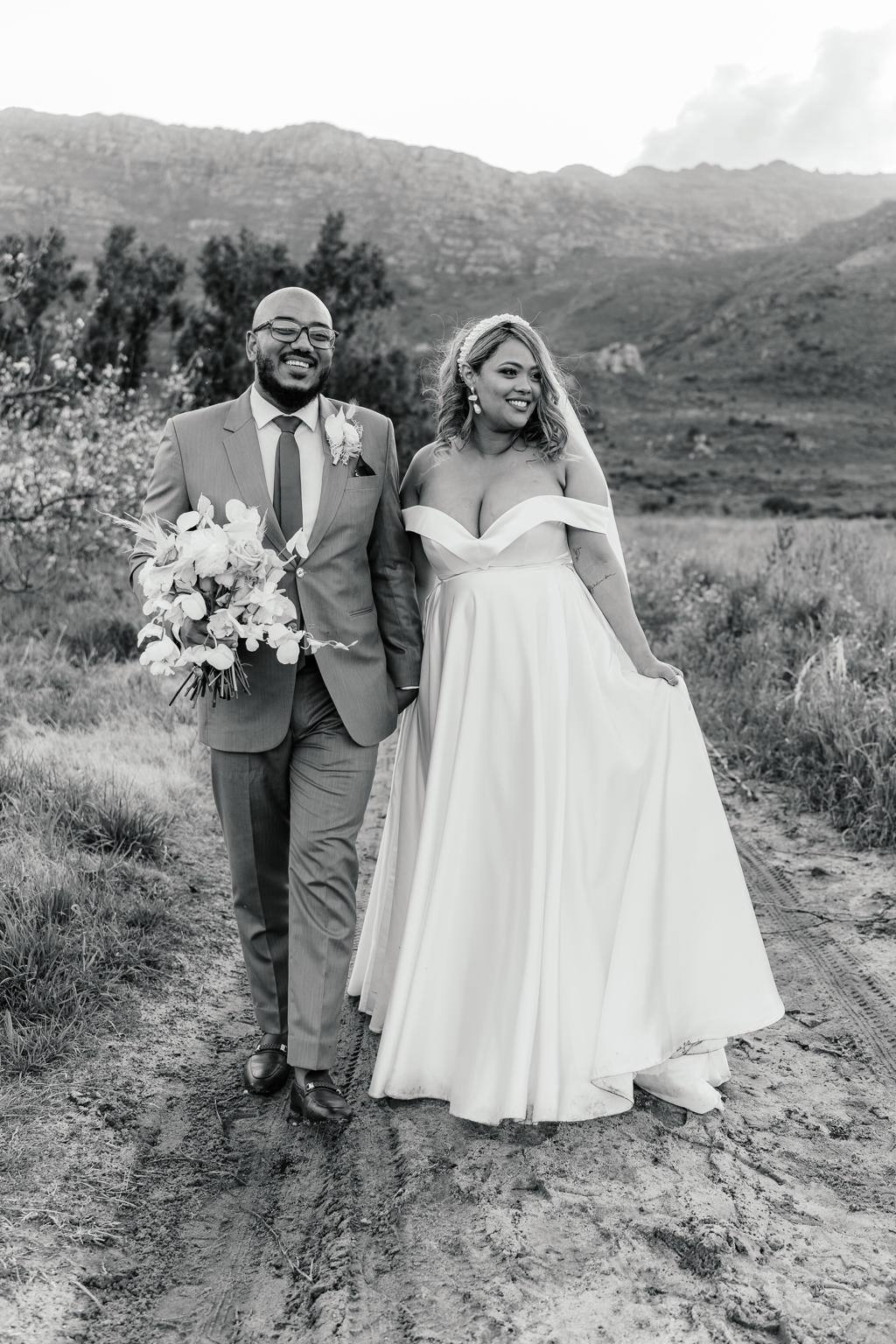 Black-and-white photo of the bride and groom walking along a mountain track, Ulrich and Keshia's wedding