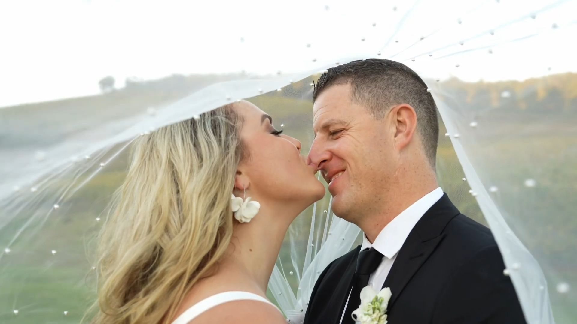 Ruaan and Leani kissing under her veil in the soft evening light