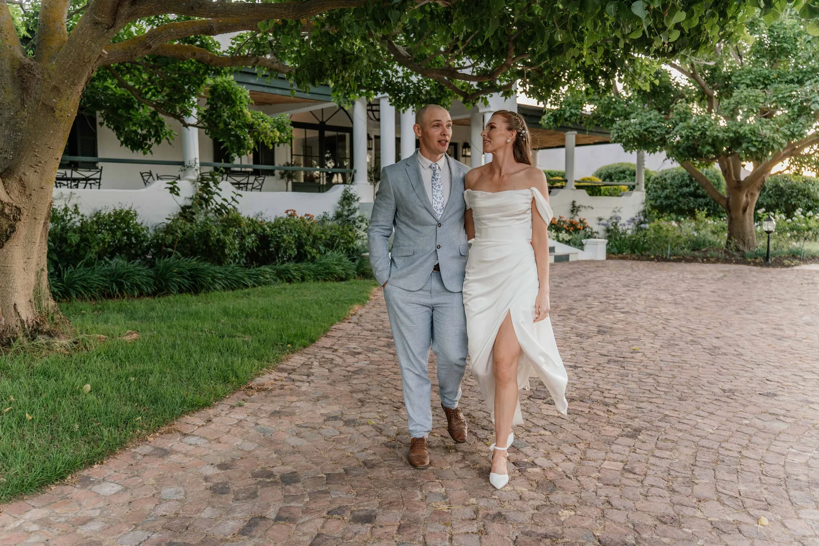 Nic and Sheree walking arm in arm along a cobbled garden path