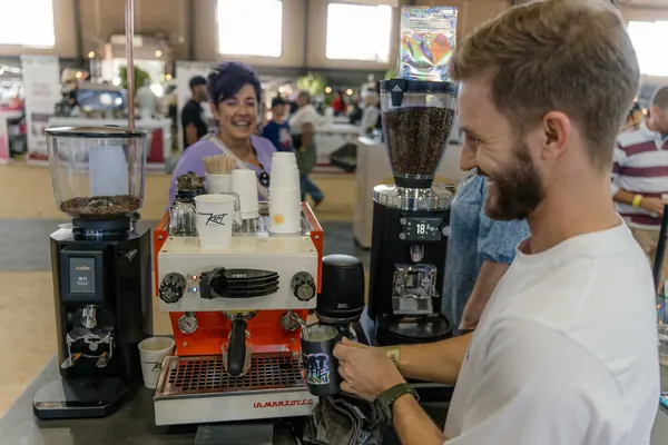 The barista at the grinders, talking customers through the coffee, Kort Coffee