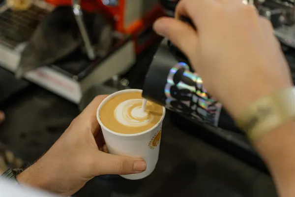 Latte art being poured into a takeaway cup, Kort Coffee
