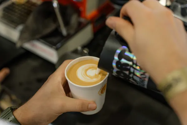 Milk poured into a flat white, the latte art forming