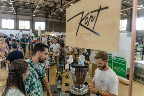 Customers chatting with the barista under the Kort sign