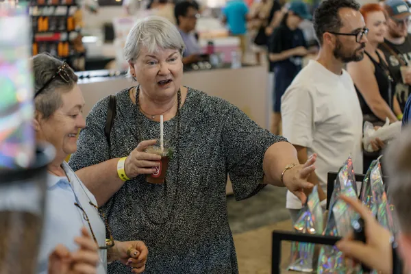 A festival-goer with a coffee in hand, chatting at the stand