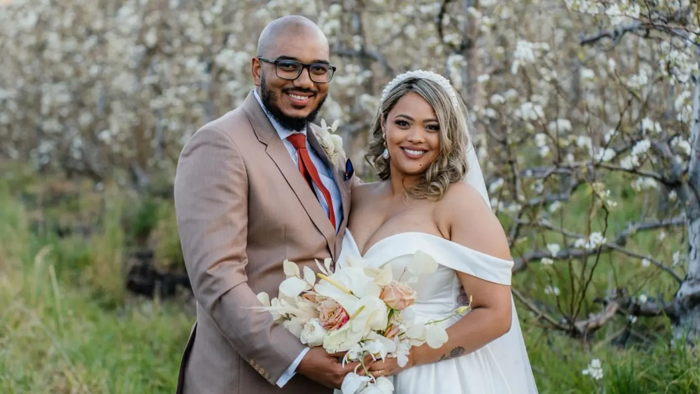 A smiling bride and groom in a blossoming orchard